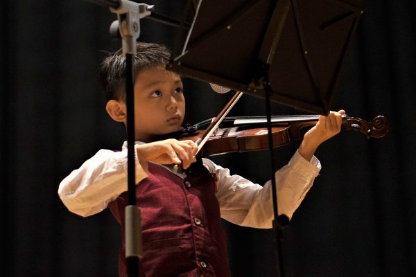 Fine Momentum music class student performing violin on stage