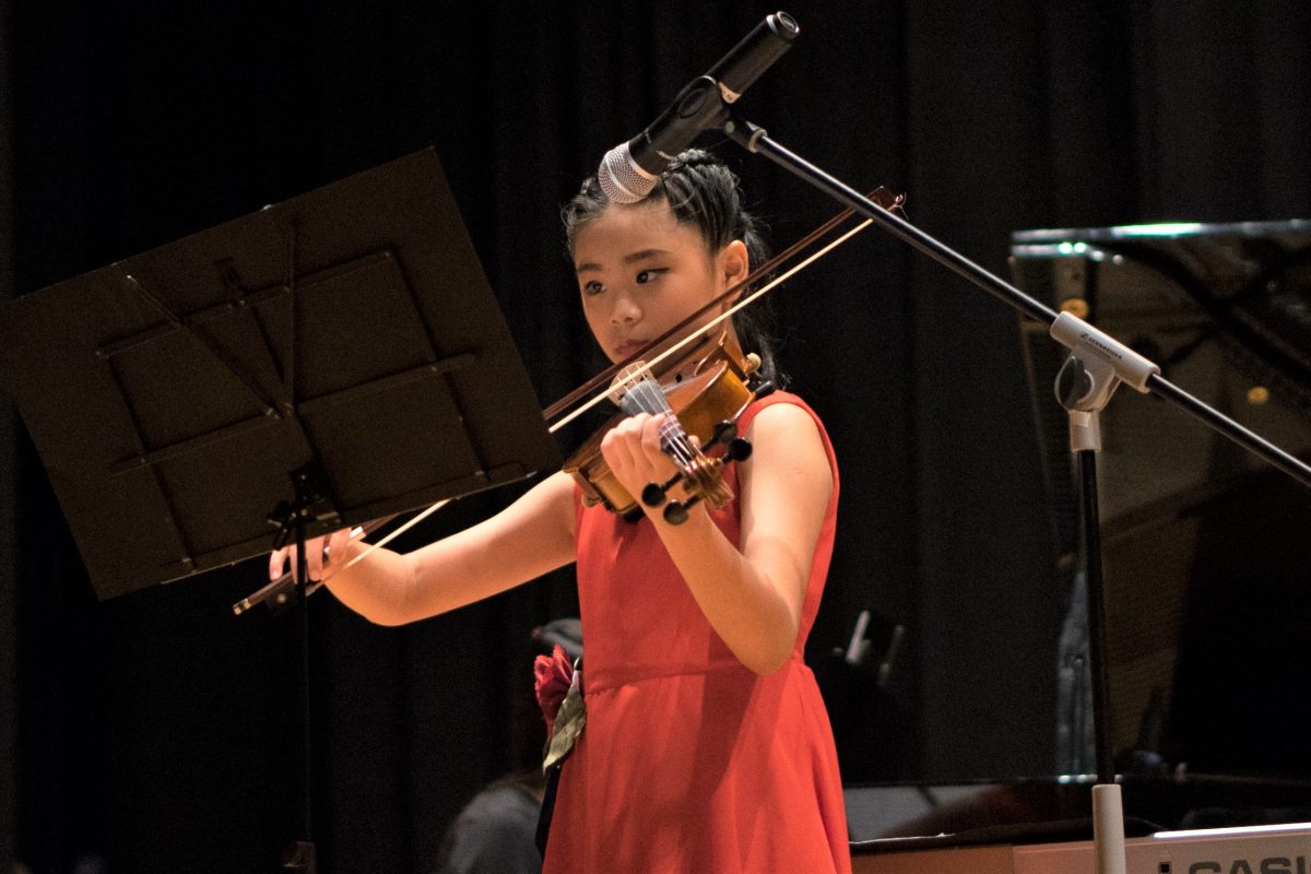 Fine Momentum music class student performing the violin on stage