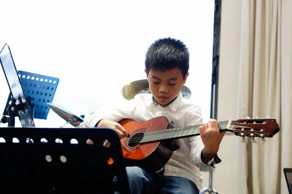 Fine momentum music lesson student performing the guitar