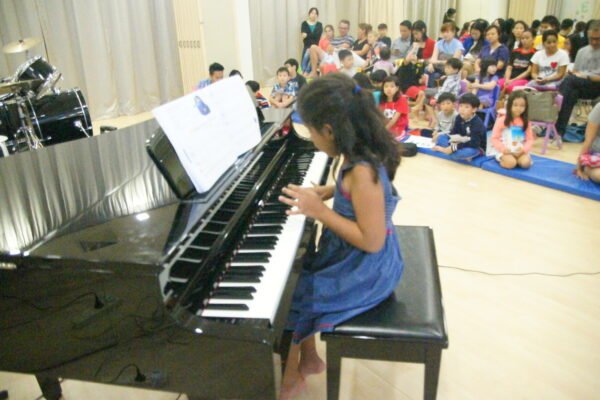 Fine momentum piano lesson for kids student performing for a big crowd