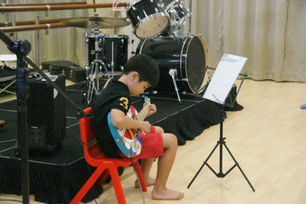 Fine momentum music class for kids students playing the guitar